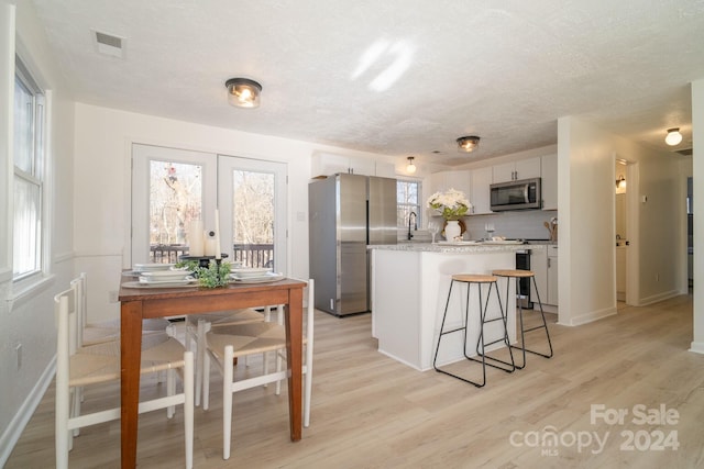 kitchen with appliances with stainless steel finishes, white cabinetry, and plenty of natural light