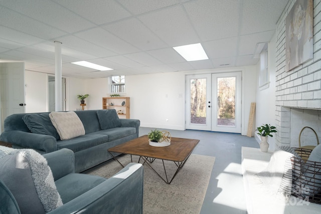 living room with french doors, concrete floors, plenty of natural light, and a drop ceiling