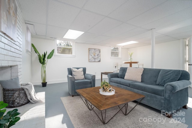 living room featuring a drop ceiling, a fireplace, and concrete floors