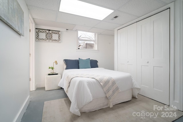 bedroom with a paneled ceiling and a closet