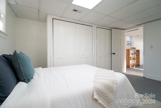 bedroom featuring a paneled ceiling and multiple closets