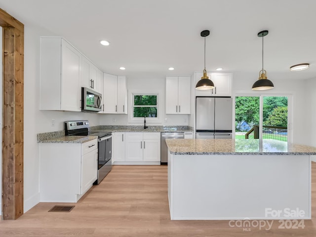 kitchen featuring white cabinetry, sink, stainless steel appliances, light hardwood / wood-style floors, and pendant lighting