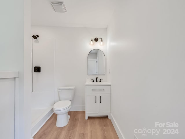 bathroom with hardwood / wood-style flooring, vanity, toilet, and walk in shower