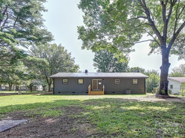 rear view of house with cooling unit and a yard