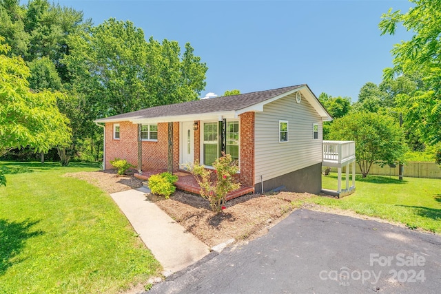 single story home featuring a front lawn and a wooden deck