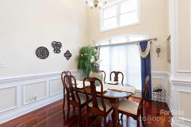 dining area with plenty of natural light, dark hardwood / wood-style flooring, a high ceiling, and an inviting chandelier