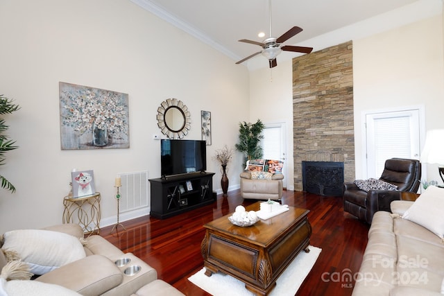 living room featuring a fireplace, a high ceiling, dark hardwood / wood-style flooring, and ornamental molding