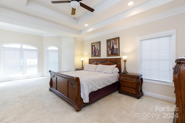 bedroom featuring a tray ceiling, ceiling fan, crown molding, and light carpet