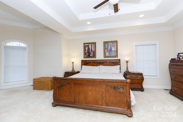 carpeted bedroom featuring a tray ceiling, ceiling fan, and crown molding