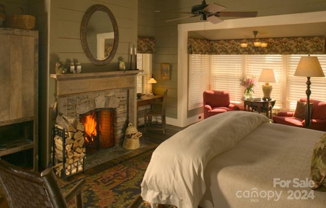 bedroom featuring a stone fireplace, ceiling fan, and wooden walls