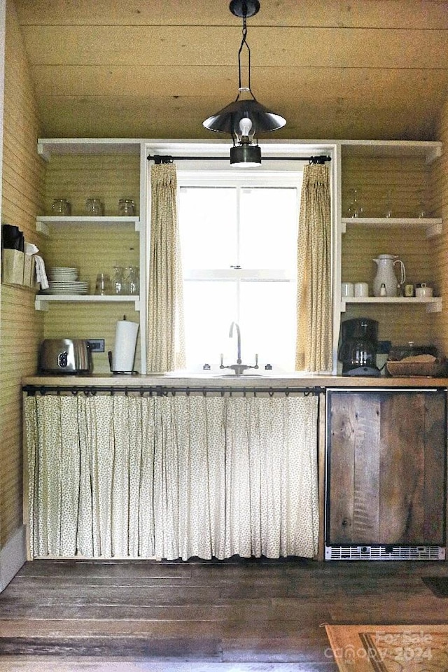 bar with hanging light fixtures, wooden ceiling, sink, and dark wood-type flooring