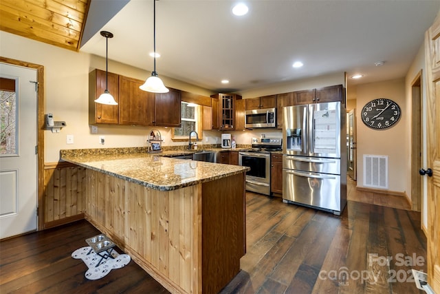 kitchen with kitchen peninsula, dark hardwood / wood-style flooring, stainless steel appliances, decorative light fixtures, and dark stone countertops