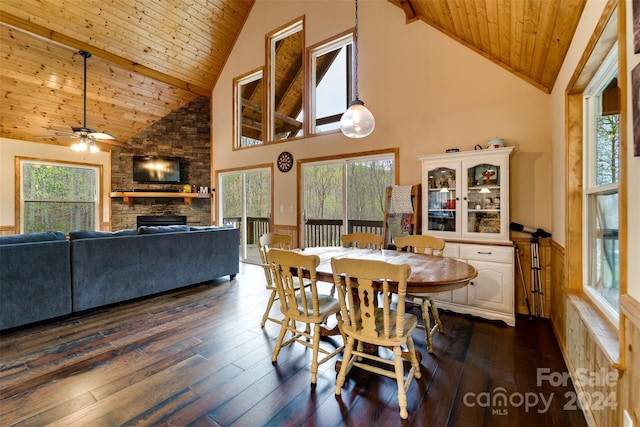 dining area with wooden ceiling, high vaulted ceiling, a stone fireplace, beamed ceiling, and dark hardwood / wood-style flooring