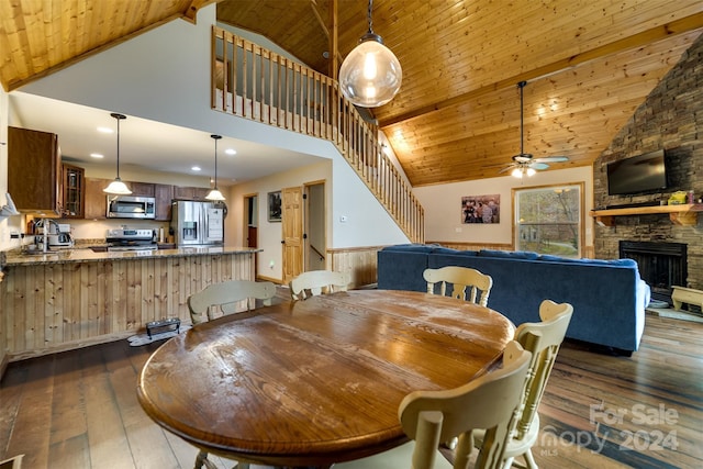 dining area with ceiling fan, wooden ceiling, dark wood-type flooring, high vaulted ceiling, and a fireplace