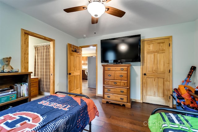 bedroom with stainless steel refrigerator, ceiling fan, and dark wood-type flooring