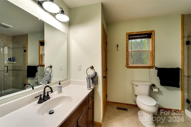 bathroom featuring tile patterned flooring, vanity, toilet, and walk in shower