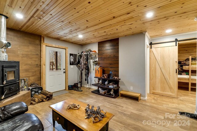 living room with a barn door, light wood-type flooring, wooden walls, and wooden ceiling