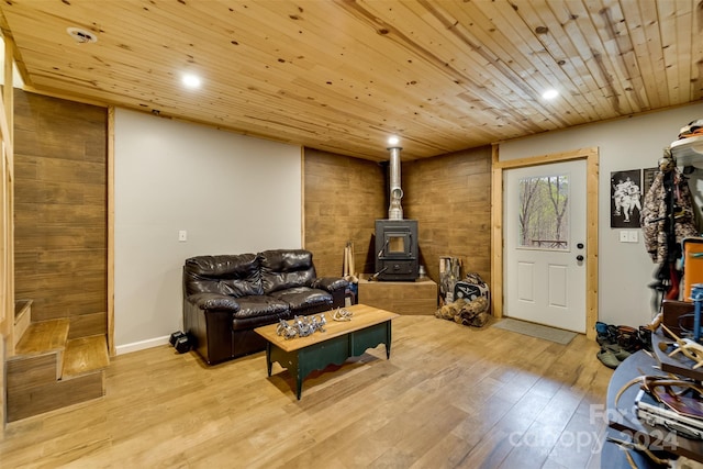 living room featuring light hardwood / wood-style floors, a wood stove, and wood ceiling