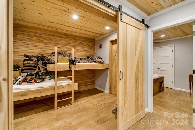 bedroom featuring wood walls, ensuite bath, a barn door, ornamental molding, and wood ceiling