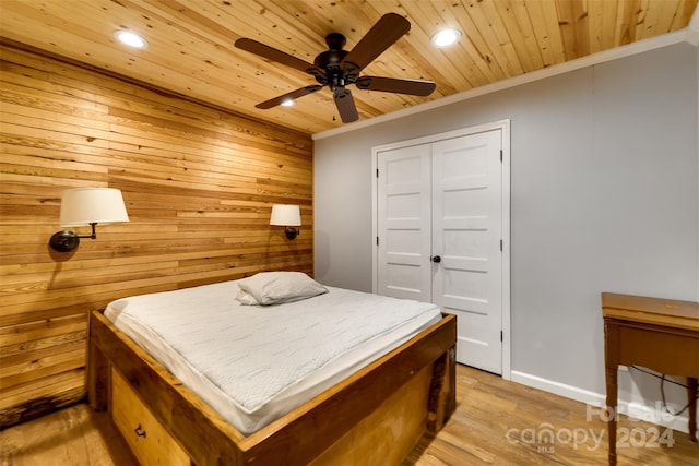 bedroom featuring ceiling fan, crown molding, wood walls, a closet, and wood ceiling