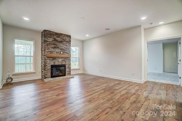 unfurnished living room with a stone fireplace and light hardwood / wood-style flooring