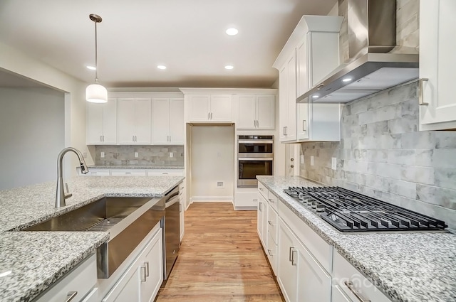 kitchen with backsplash, light stone countertops, wall chimney range hood, and white cabinets