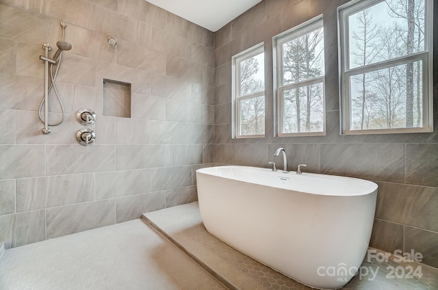 bathroom with tile walls, a bathing tub, and tile patterned flooring