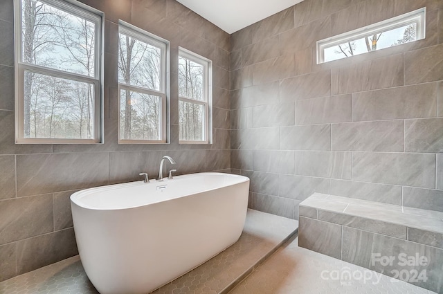 bathroom with tile walls, tile patterned floors, and a tub