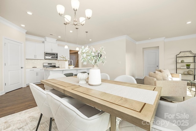 dining space featuring sink, crown molding, dark hardwood / wood-style floors, and a chandelier