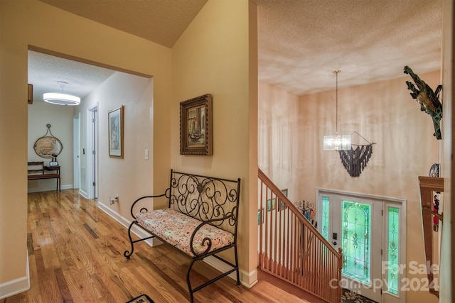 interior space featuring hardwood / wood-style flooring, a textured ceiling, and a notable chandelier