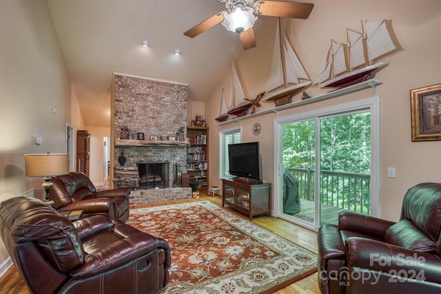 living room featuring hardwood / wood-style flooring, ceiling fan, high vaulted ceiling, and a brick fireplace