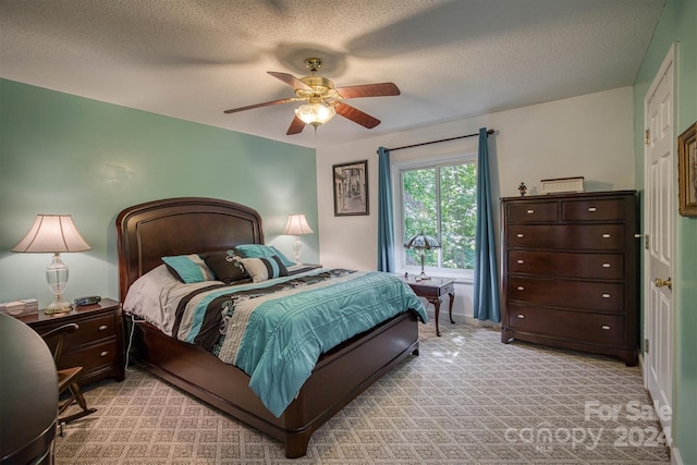 carpeted bedroom featuring ceiling fan and a textured ceiling