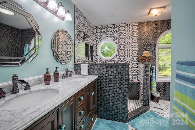 bathroom featuring tile patterned flooring, a tile shower, vanity, and tile walls