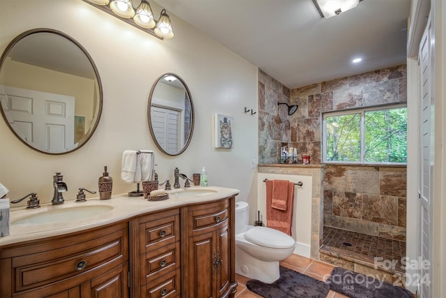 bathroom featuring a tile shower, vanity, toilet, and tile patterned floors