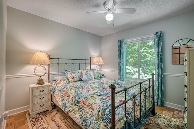 bedroom featuring a textured ceiling, light parquet flooring, and ceiling fan