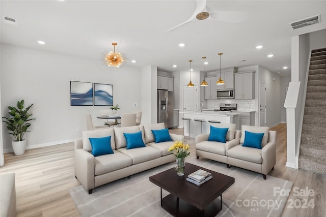 living room with ceiling fan, light wood-type flooring, and sink