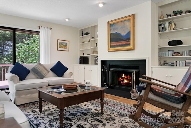 living room with wood-type flooring and built in shelves