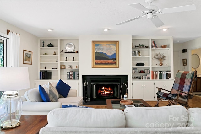 living room featuring ceiling fan, wood-type flooring, and built in shelves