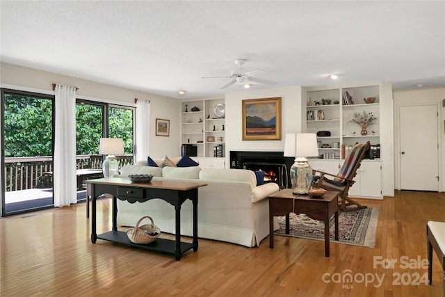 living room featuring ceiling fan, built in features, and light hardwood / wood-style flooring