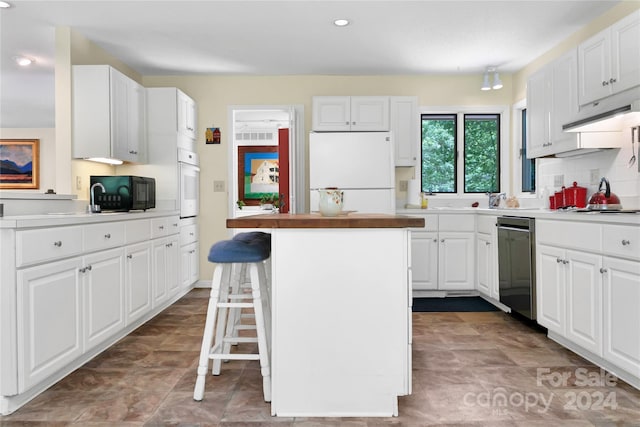 kitchen with a breakfast bar, white appliances, white cabinets, and a kitchen island