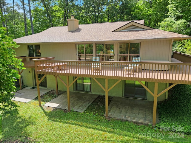 back of house featuring a deck, a patio area, and a lawn