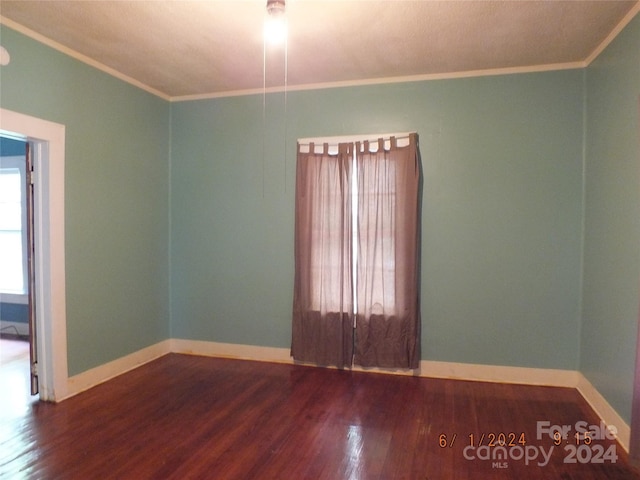 spare room featuring dark wood-type flooring and ornamental molding