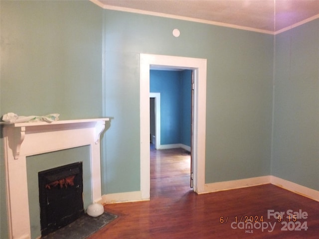 unfurnished living room featuring dark hardwood / wood-style flooring and ornamental molding