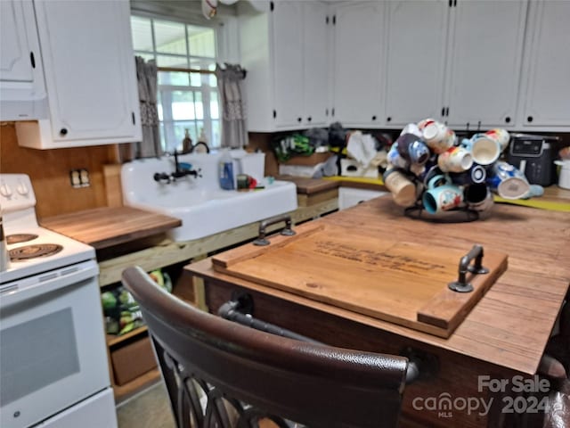 kitchen featuring sink, white range with electric stovetop, and white cabinetry