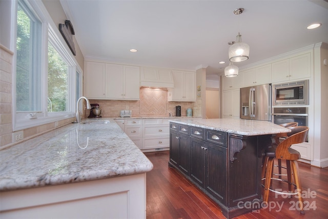 kitchen featuring sink, stainless steel appliances, a center island, and white cabinetry