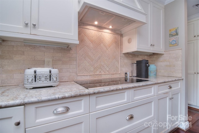 kitchen featuring custom exhaust hood, backsplash, white cabinets, and black electric stovetop