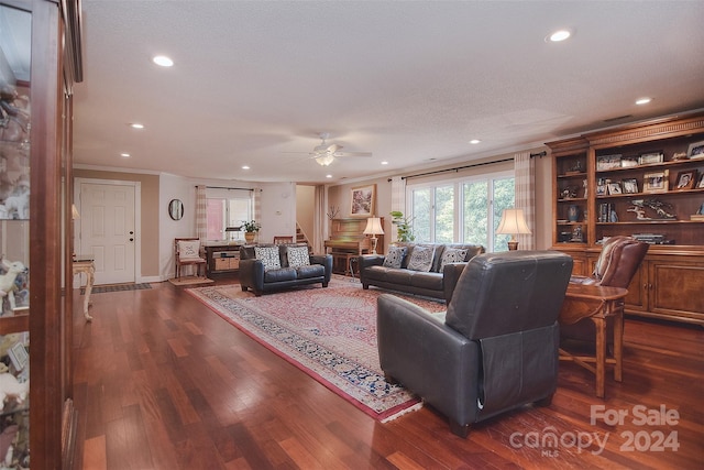 living room featuring ceiling fan, a textured ceiling, dark hardwood / wood-style floors, and crown molding