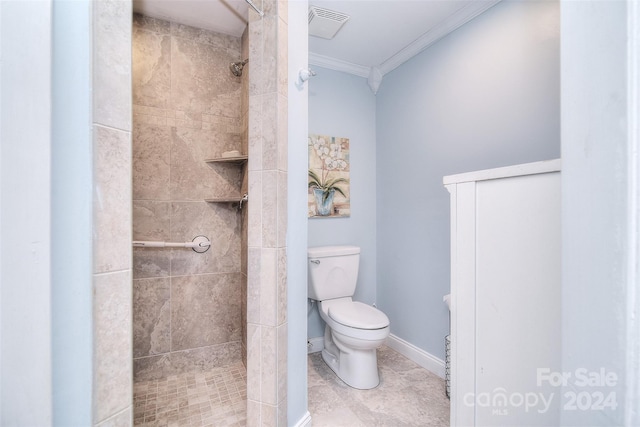 bathroom featuring tiled shower, toilet, and ornamental molding