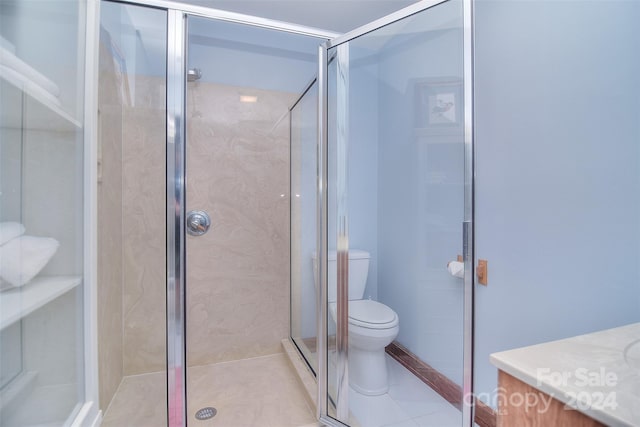 bathroom featuring vanity, toilet, tile patterned floors, and a shower with door