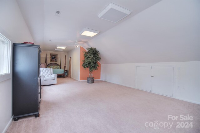 additional living space featuring ceiling fan, light colored carpet, and lofted ceiling